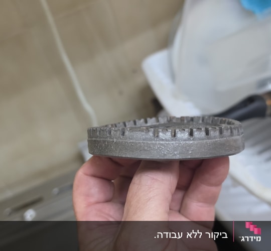 ראש מבער של כיריים גז מוחזק ביד במהלך תיקון